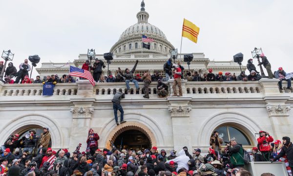 Rioters climbing on the U.S. Capitol, waving flags