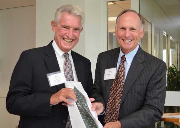 Gerald Fox holds a UNC Charlotte tie standing next to then-Chancellor Phil Dubois