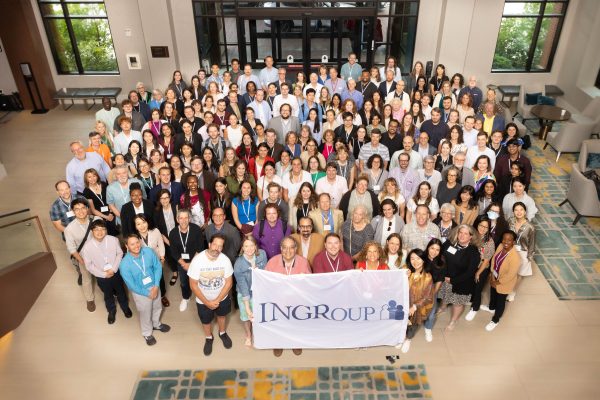 A group of about 200 INGRoup conference attendees, with the front row holding a banner of the logo.