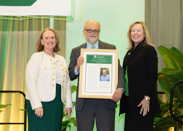 Mark West holds his large framed recognition standing between Provost Troyer and Chancellor Gaber.