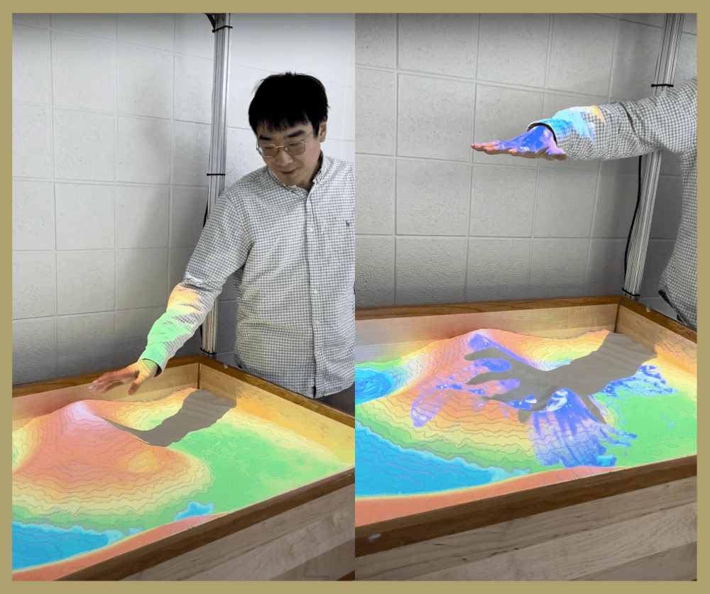 Left: Man stands over the sandbox with brightly colored light projected on the sand depicting elevation. Right: his hand hovers a foot above the sandbox and the projection adds rain to the mountain.