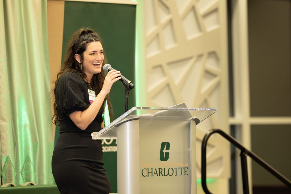 Hannah Javidi holds the microphone while speaking at the podium