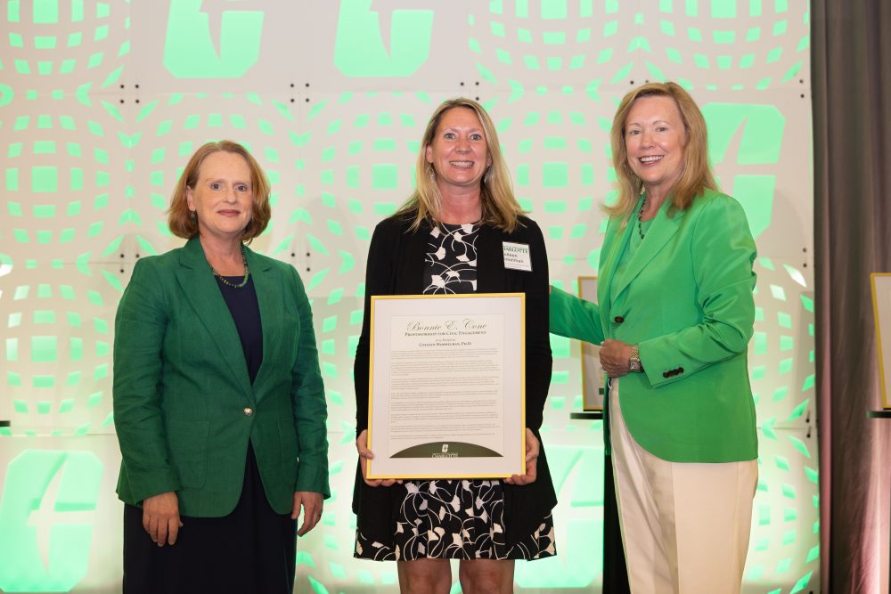 Colleen Hammelman holds framed award between Provost Jennifer Troyer and Chancellor Sharon L. Gaber.