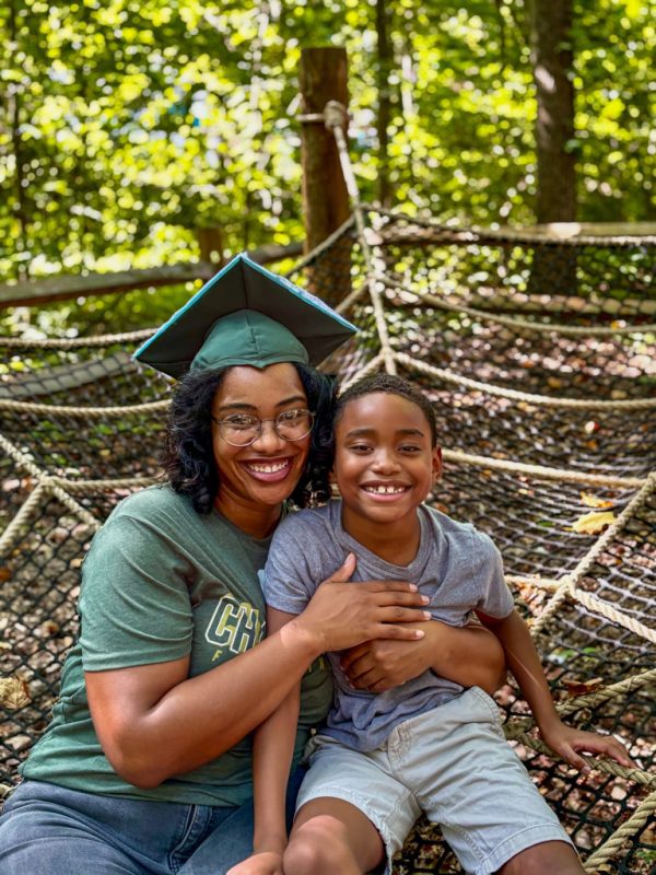 Skylar Triotta wears her graduation cap and hugs her son in the Botanical Gardens.