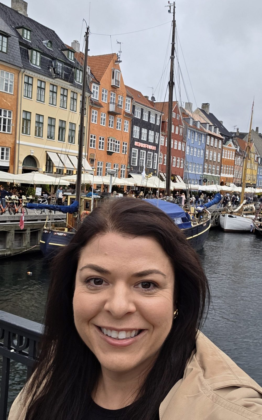 Jaclyn Piatak posing in front of colorful buildings, boats, and water in Copenhagen, Denmark.
