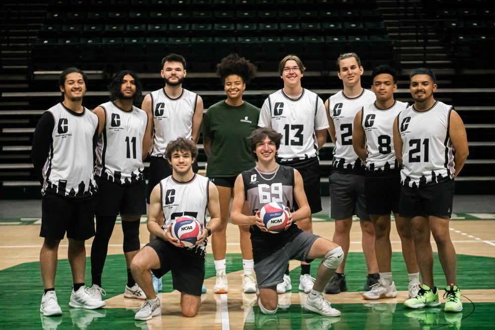 Madison Black wears a UNC Charlotte shirts and standing the middle of the team photo with the men's club volleyball team wearing jerseys.