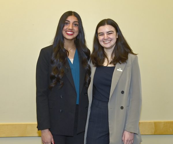 Hill posing with Noorkaran (Noor) Chima against a plain wall.