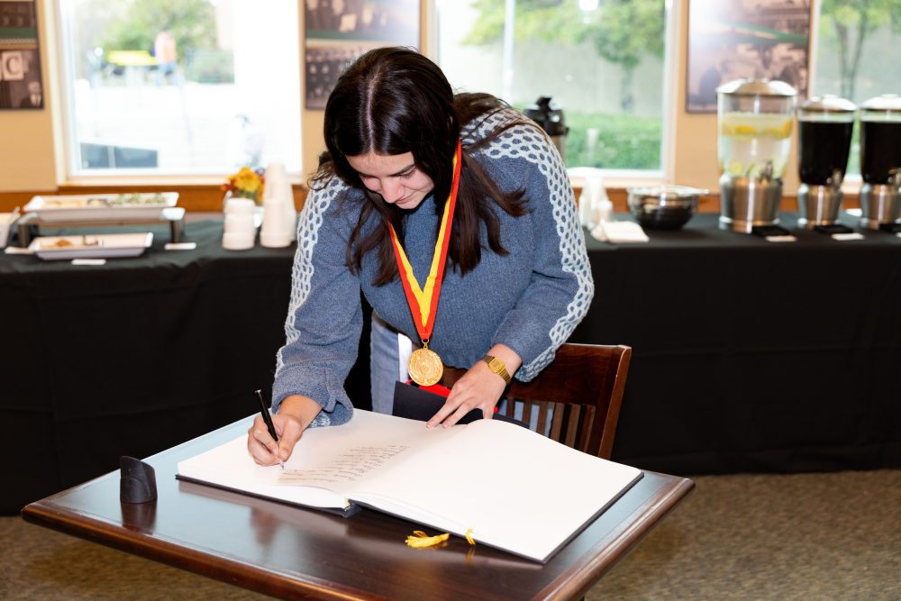 Hill signing the Phi Beta Delta induction book.