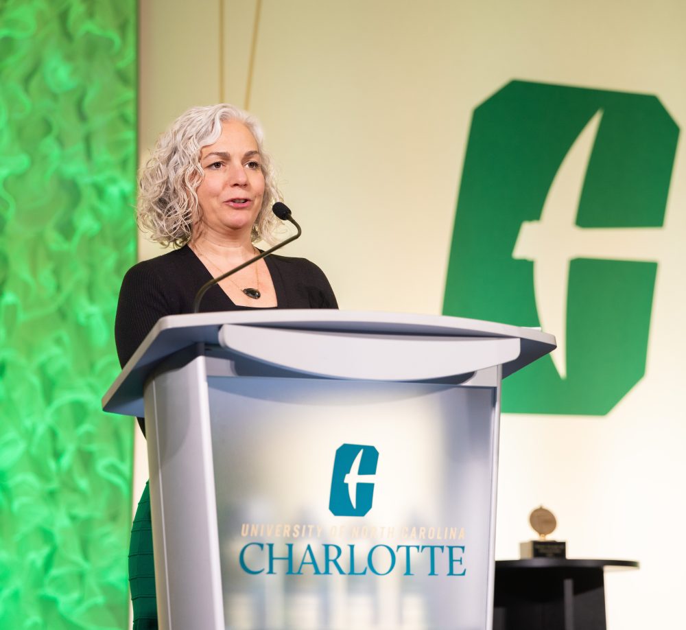 Laura Yates Clark speaks at the podium while accepting the UNC Charlotte Distinguished Alumni Award