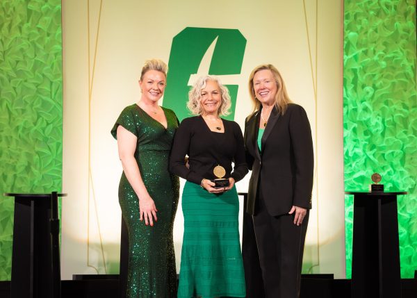 Laura Yates Clark holds her award on a UNC Charlotte stage, standing in between Summer Baruth and Chancellor Sharon L. Gaber.
