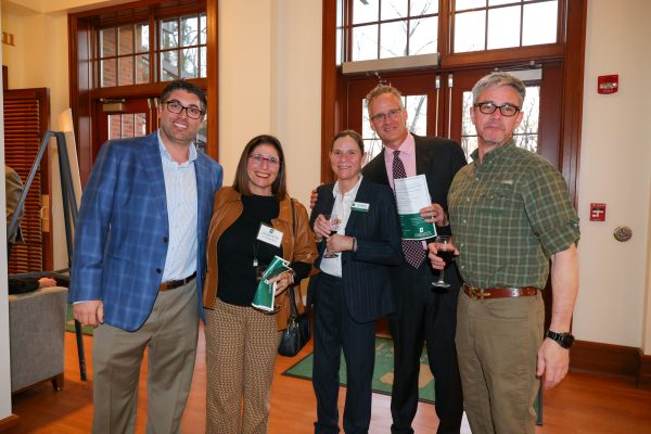5 people stand smiling in the lobby of the Harris Alumni Center