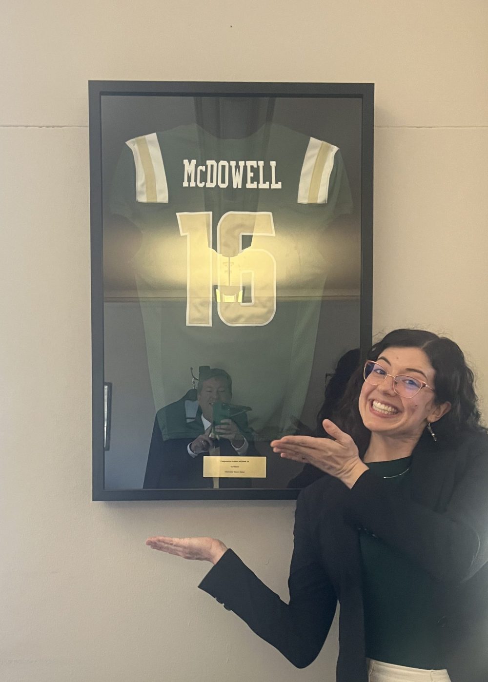 Elliott smiling in front of a UNC Charlotte jersey that says "McDowell"