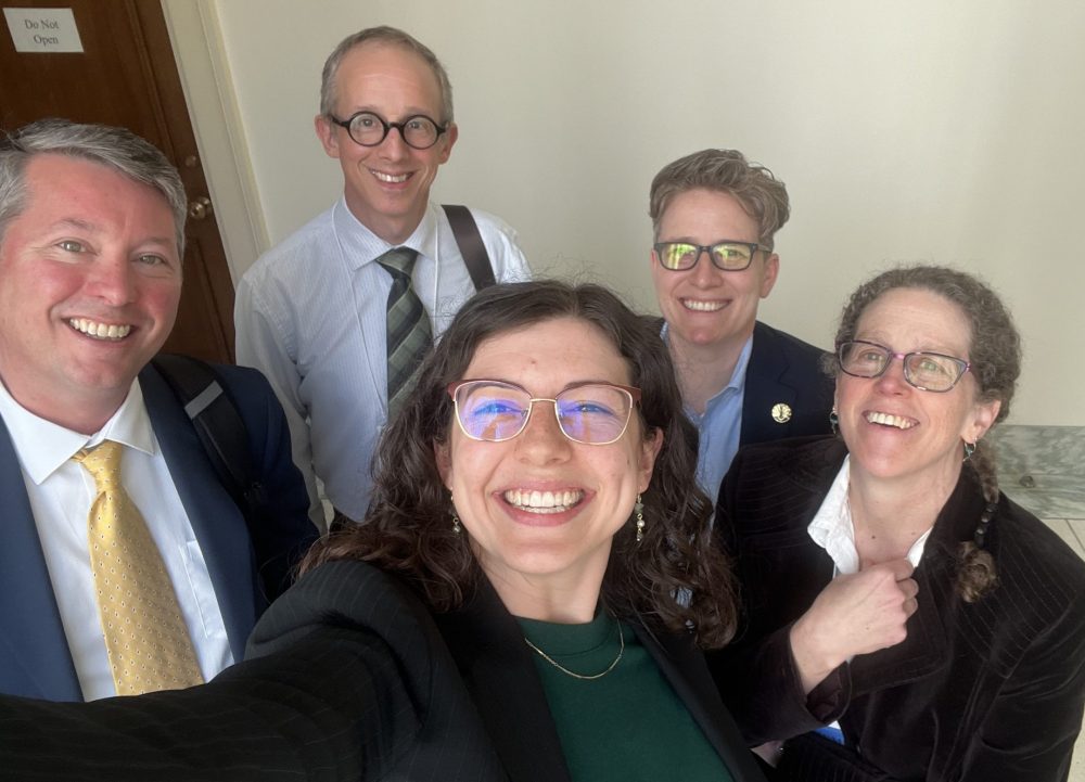 Elliott holding the camera out to take a selfie, with four people smiling in the background.
