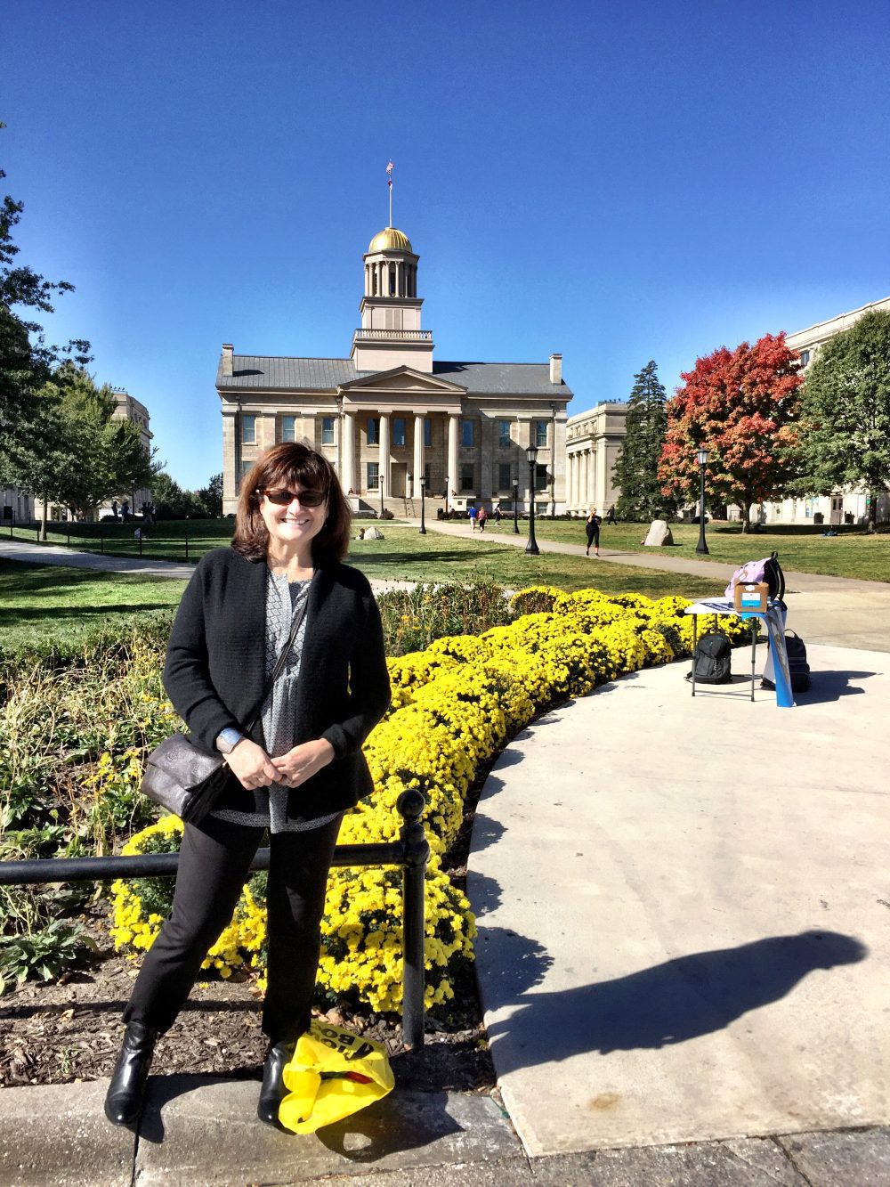 Blitvich posing in front of an academic building on campus at the University of Iowa. A table is set up in the background.