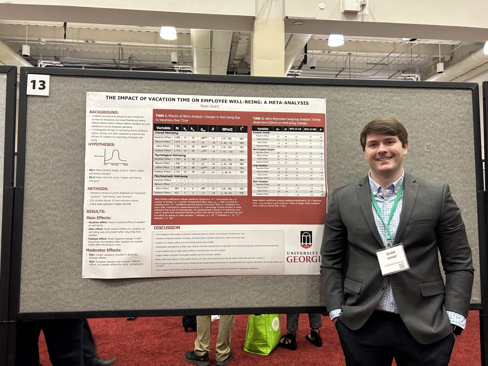 Ryan Grant posing in front of his research poster.