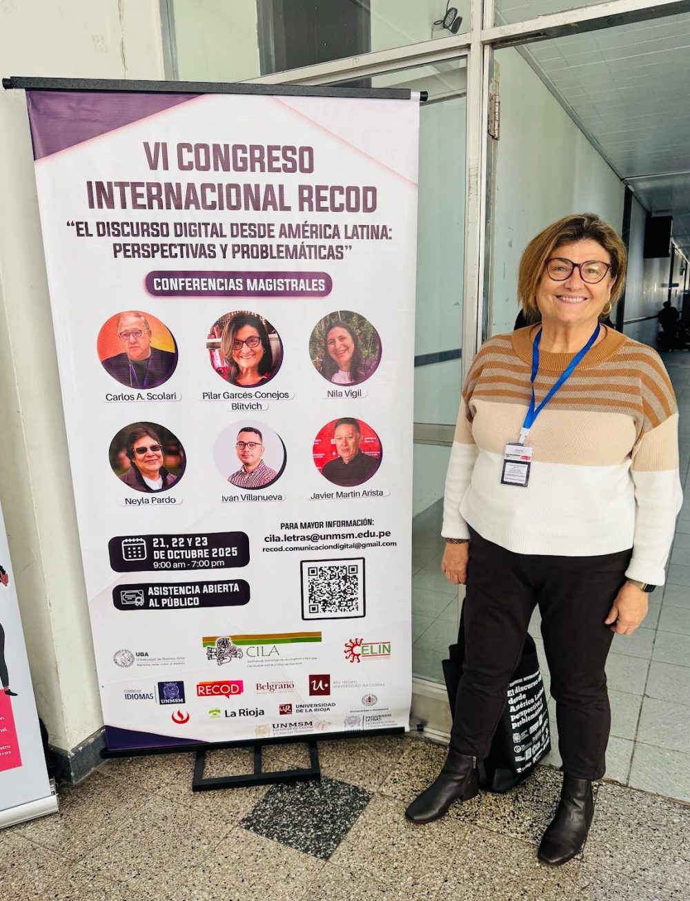 Blitvich posing next to a banner advertising the RECOD conference. Her headshot is on the banner alongside other presenters.