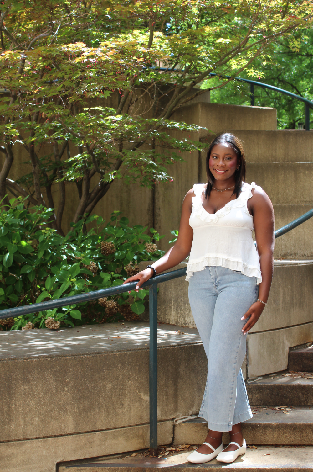 Frink poses on stairs with a hand on the railing.