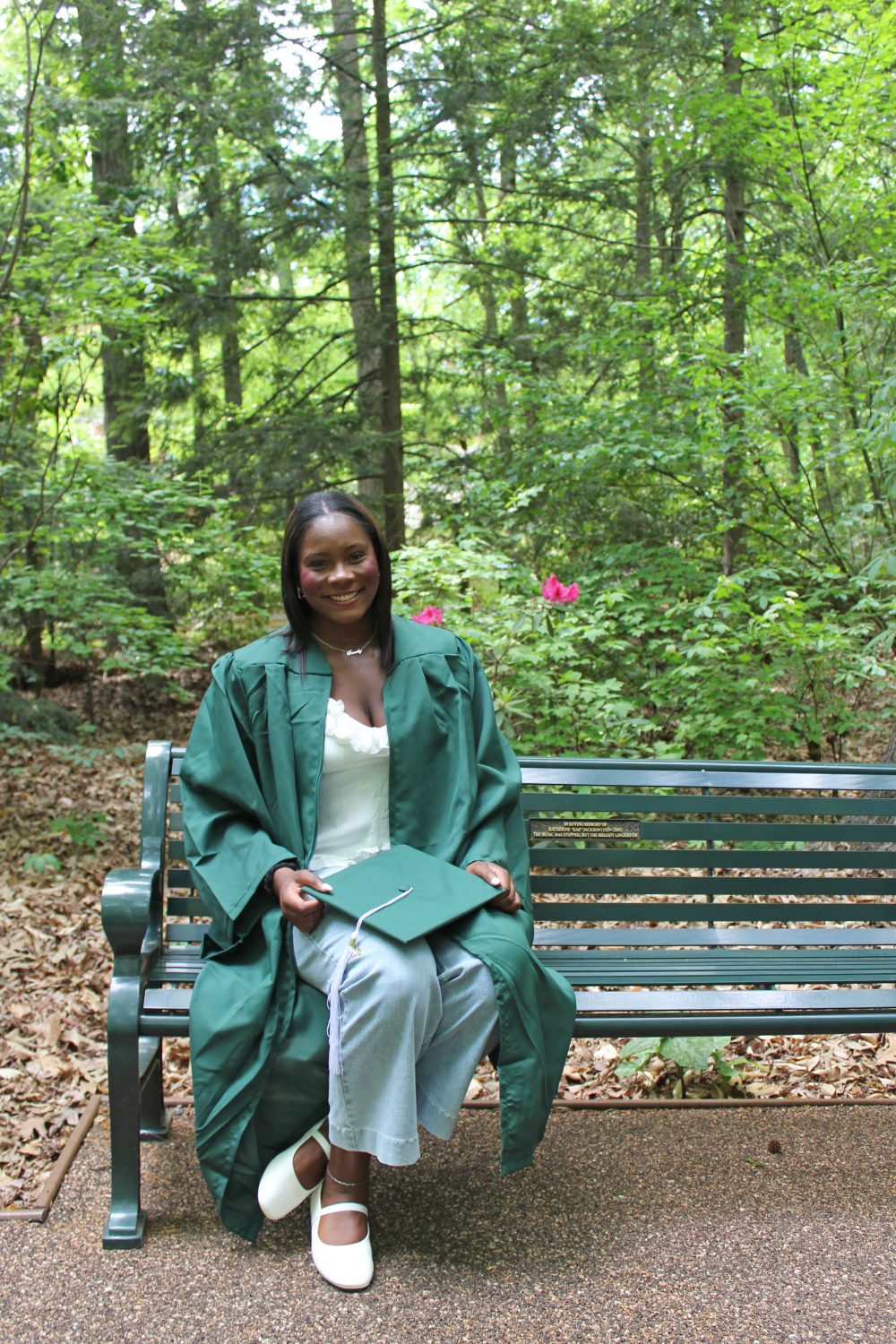 Frink sitting on a bench holding her graduation cap.