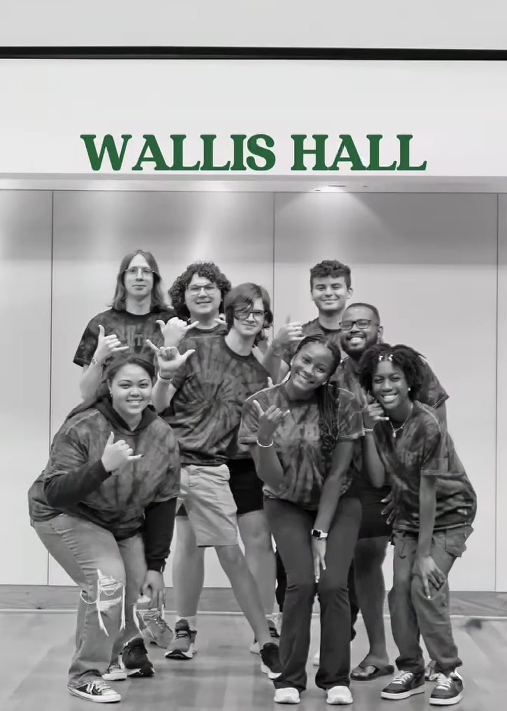 Frink and seven resident advisors pose in front of green Wallis Hall sign.