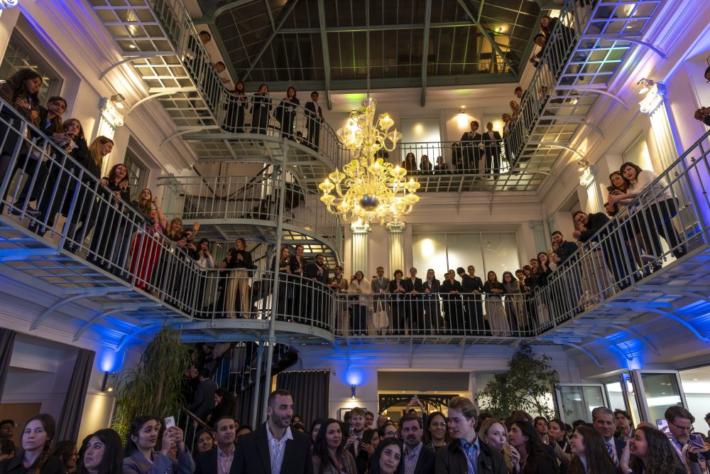 A large crowd at the ICC Mediation Week event. People stand on the main floor and on two balcony levels as well.