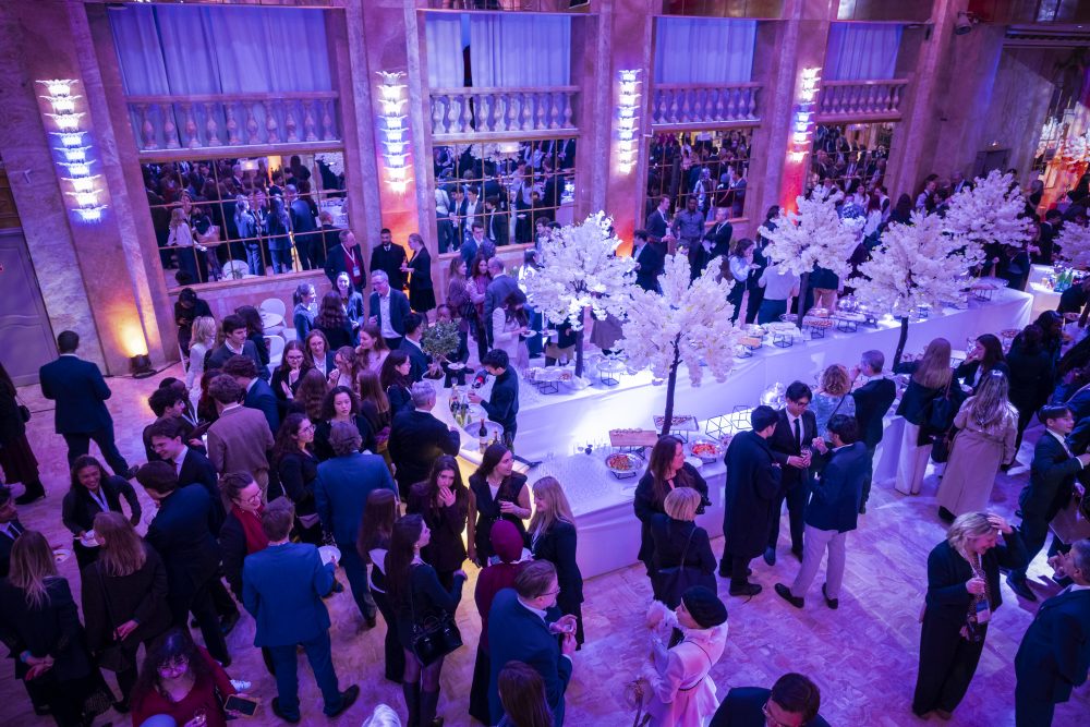 The opening cocktail party, with attendees talking around a bar with food and drinks.
