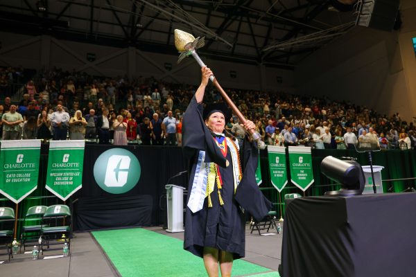 UNC Charlotte's Susana Cisneros wears graduation regalia on stage and presents the mace to the crowd at the spring commencement ceremony.