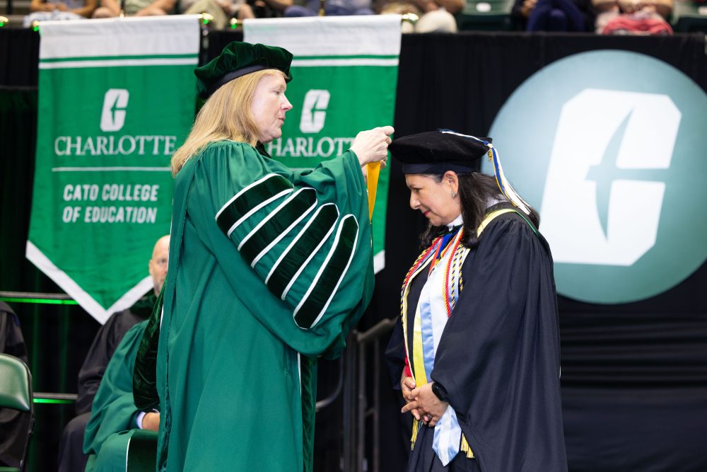 UNC Charlotte Chancellor Sharon L. Gaber puts a medal with a yellow ribbon over the head of Susana Cisneros.