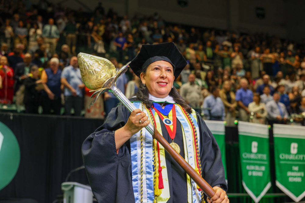 Susana Cisneros, senior lecturer of Spanish, holds the mace on sage at UNC Charlotte's commencement,.