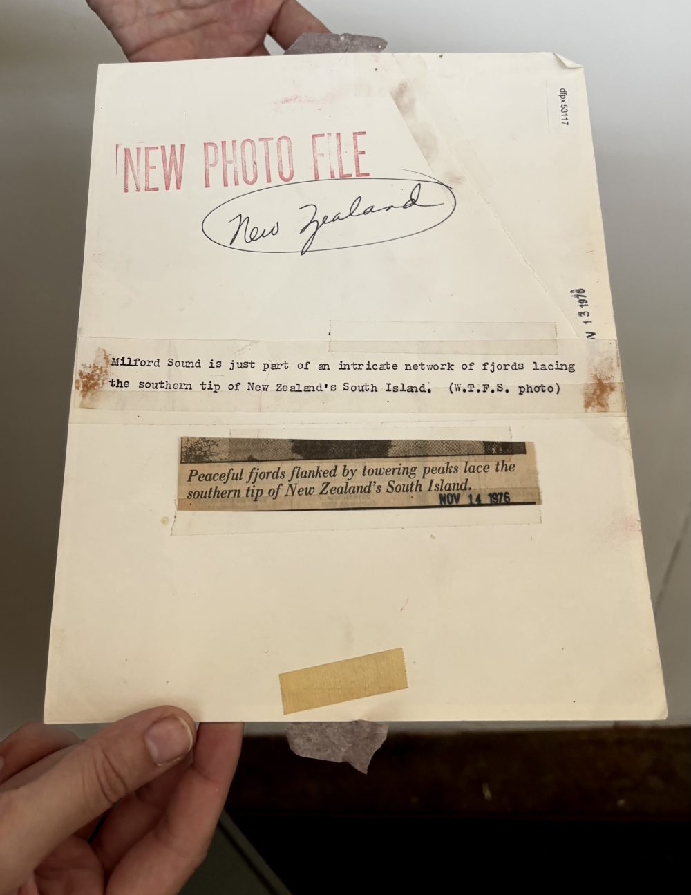 Hands holding the back of the black and white photograph of a mountain in New Zealand dated November 14, 1976.