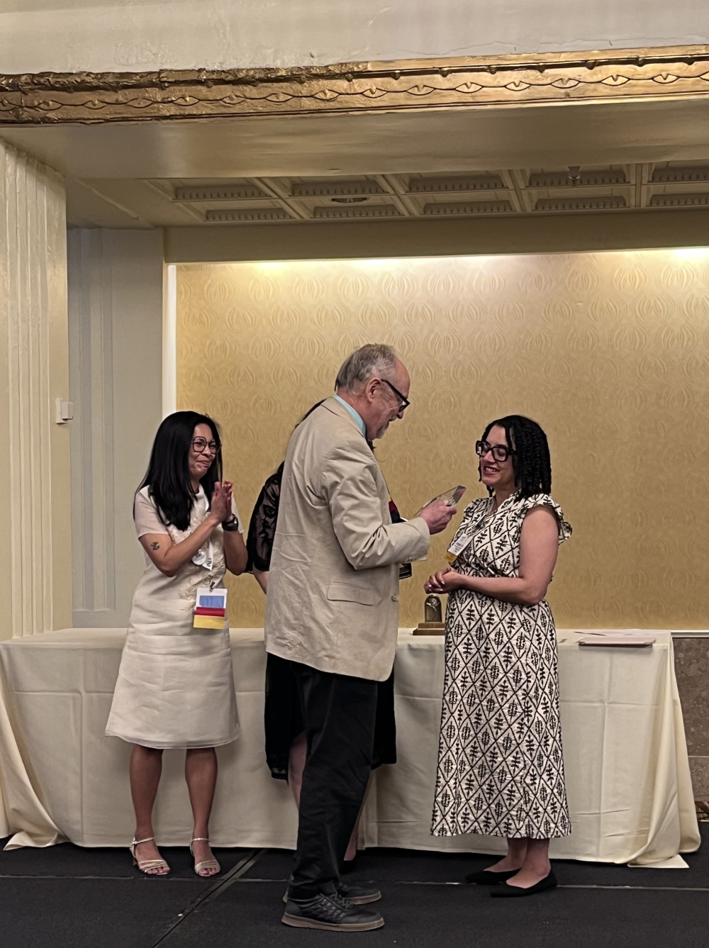 West onstage receiving his award from three members of the award committee.