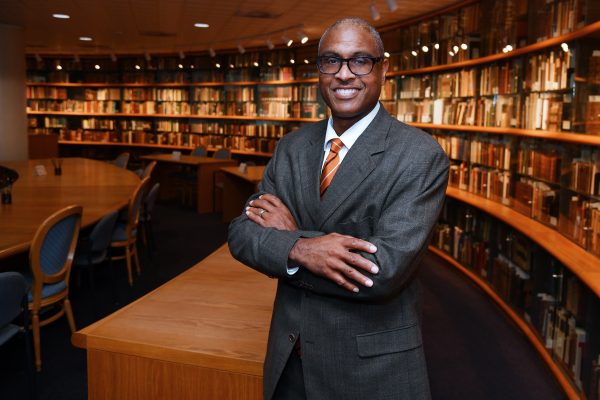 Jeffrey B. Leak stands smiling in Atkins library surrounded by books.
