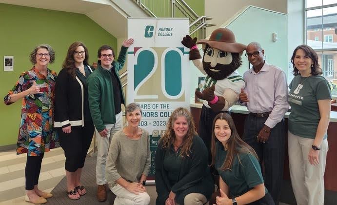 Jeffrey Leak stands next to Norm the Niner, with colleagues from the Honors College.
