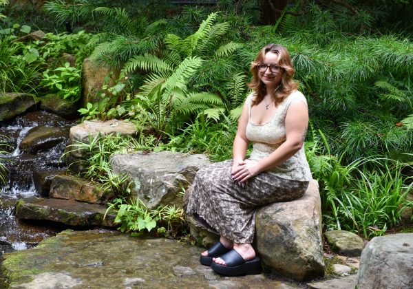 Mayah Clark, UNC Charlotte anthropology student in the College of Humanities & Earth and Social Sciences who conducted undergraduate and honors research, sits near a pond in the UNC Charlotte Botanical Gardens.