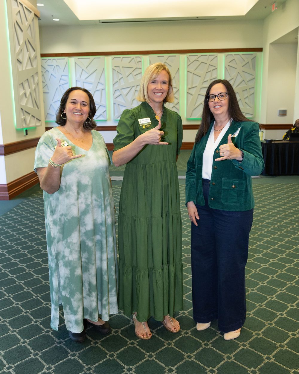 Three 2026 ACE winners, Shannon Homesley, Suzanne Voigt, Tonya Bates, smile while wearing green clothings and holding up pickaxe hand signs.