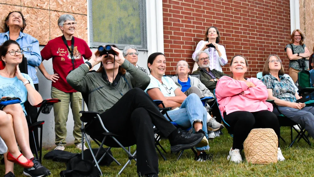 Happy attendees sit in fold out chairs while watching the birds.